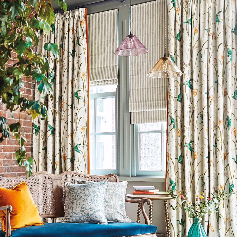 Sitting room with patterned curtains, a striped Roman blind, and matching cushions on an upholstered sofa.