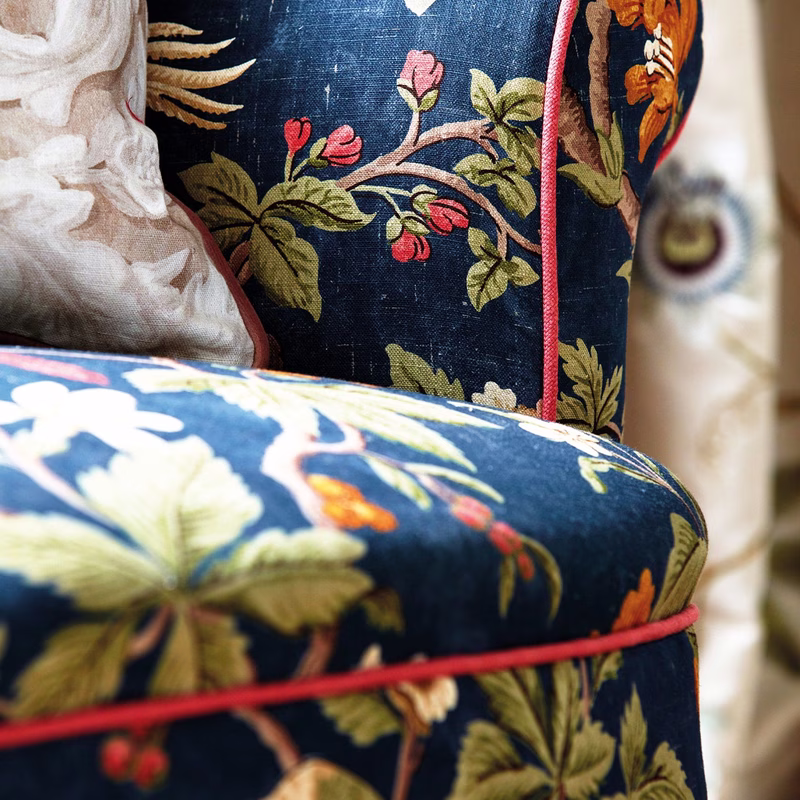 Close-up of a chair upholstered in patterned fabric, with a matching cushion or backrest behind it.