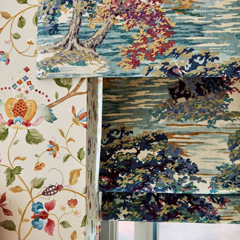 Interior fabric display showing Ancient Canopy on layered Roman blinds beside a floral print fabric panel.