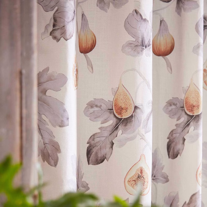 Close-up of fig-printed fabric hanging as curtains in a room, with soft gathered folds.