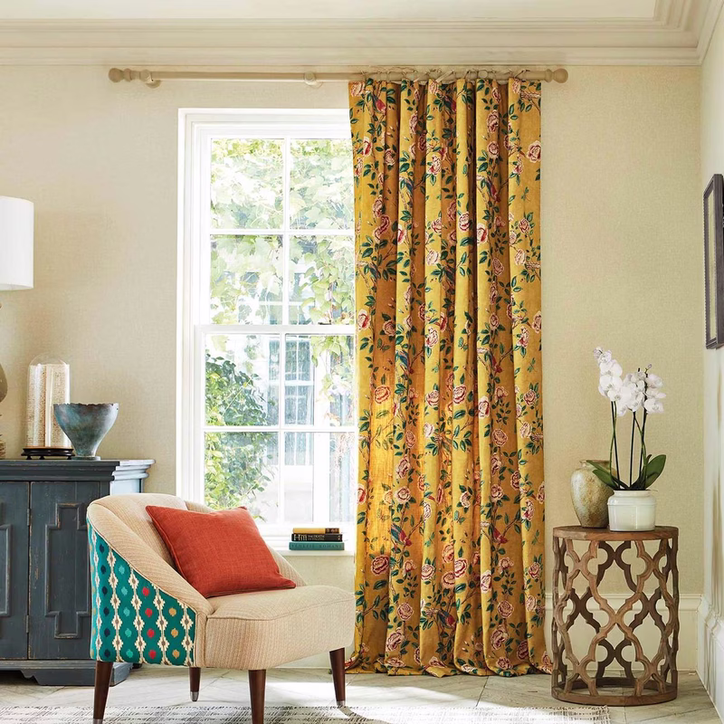 A living room with floral patterned curtains hung at a window, the fabric made up as full-length curtains.