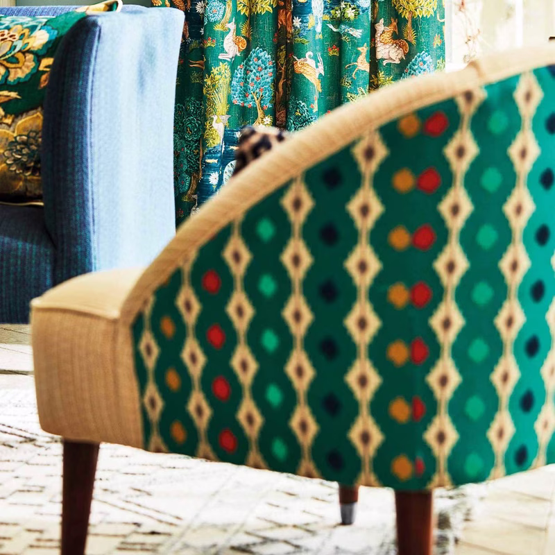 An upholstered armchair in a room with matching patterned curtains and cushions, covered in Mossi fabric.
