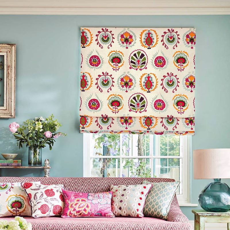 Sitting room with a Roman blind made in a bright circular floral print, plus a patterned upholstered sofa with cushions.