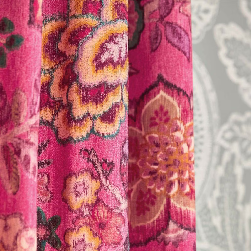 Close-up of pink floral patterned fabric shown as hanging curtains with gathered folds.