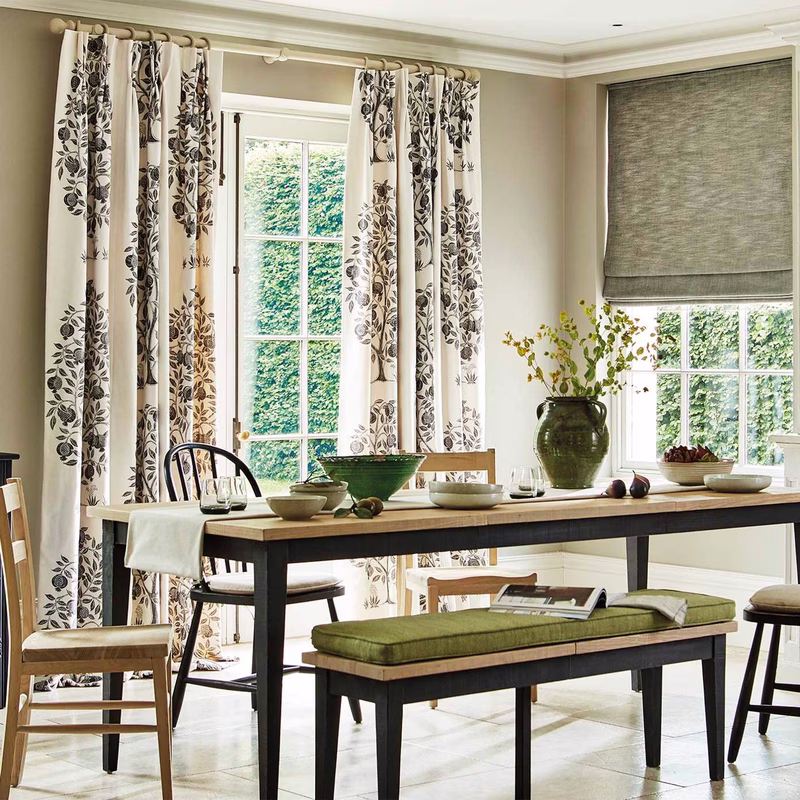 Dining room with floor-length patterned curtains and a grey Roman blind at the window.