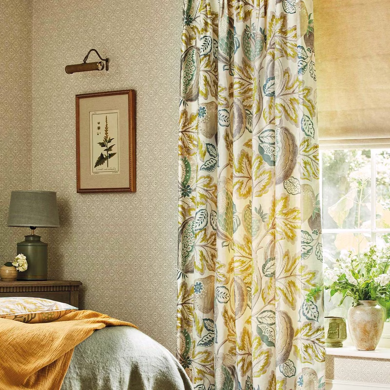 Bedroom scene with floral fabric made up as curtains beside a bed, showing the Cantaloupe print in a large drape at the window.