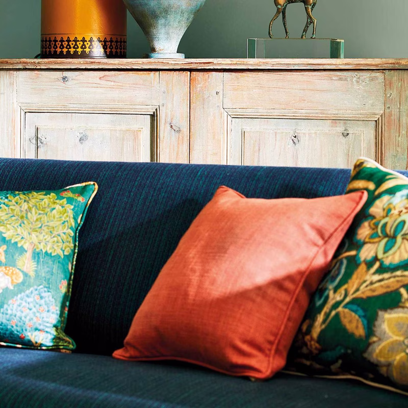 Living room scene with a deep blue sofa upholstered in the fabric, with three cushions on it.