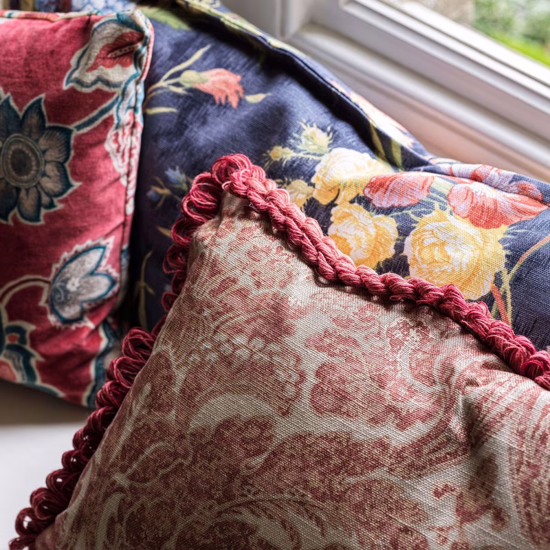 Three patterned cushions on a windowsill, made up with contrasting trims and fringe.