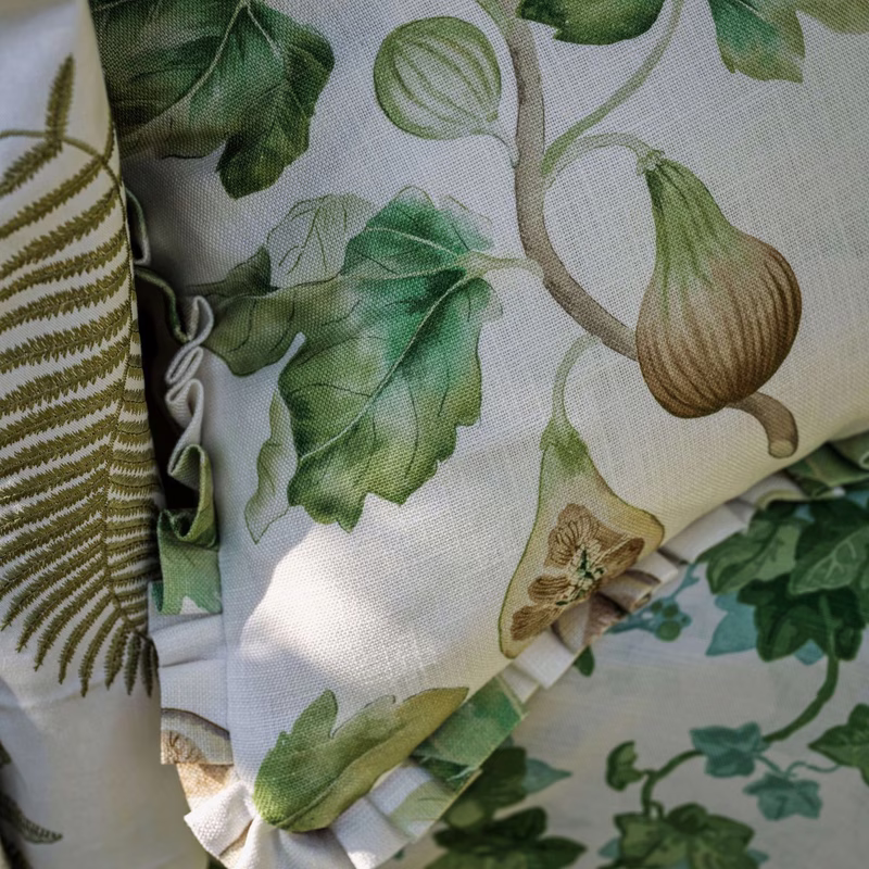 Close-up of patterned fabric swatches, with fig and leaf print made up as gathered cushion covers or samples.