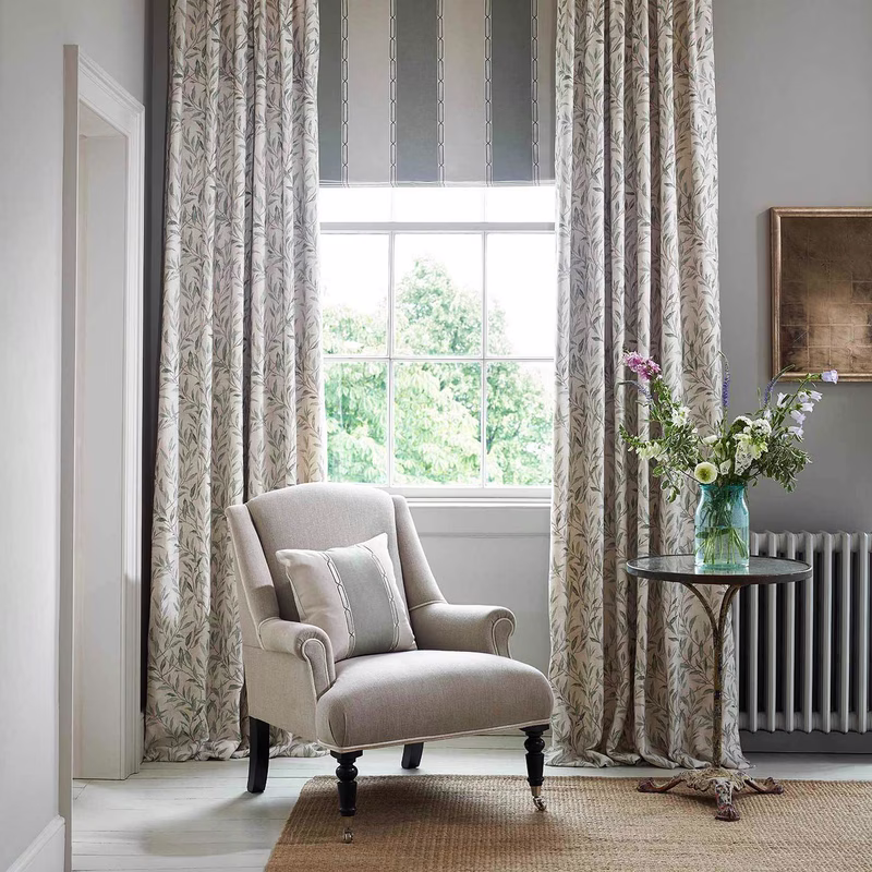 Living room with floor-length patterned curtains framing a window and a coordinating upholstered armchair with cushion.