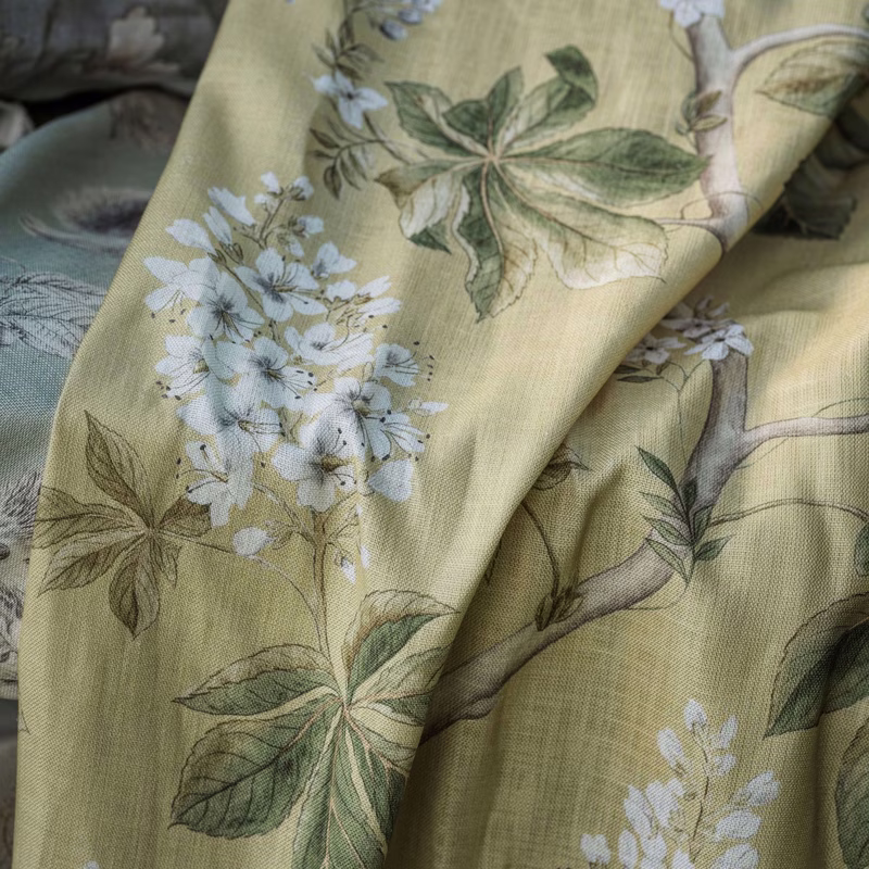 Close-up of a floral and leaf patterned fabric draped in folds, showing the cloth as upholstery fabric.