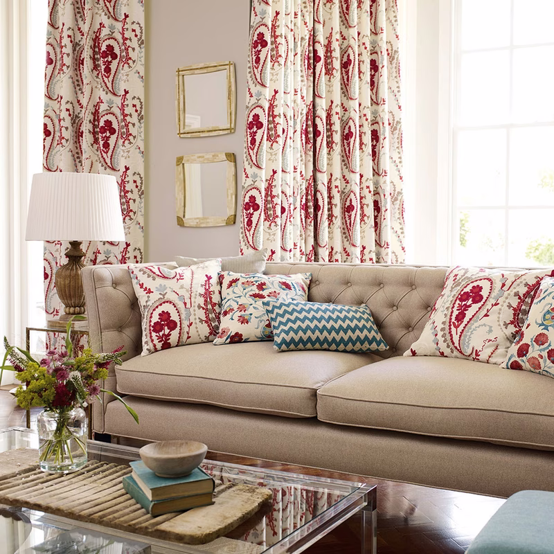 A living room with Jamila fabric made up as curtains and cushions, shown with a sofa and window light.