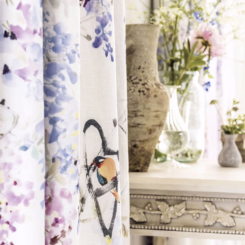 Interior with Wisteria Falls fabric shown as curtains beside a decorated console table and vases.