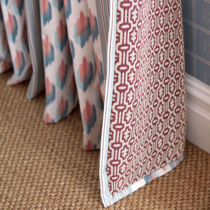 Room with patterned curtains and a matching fabric sample hanging beside them, shown as curtains.