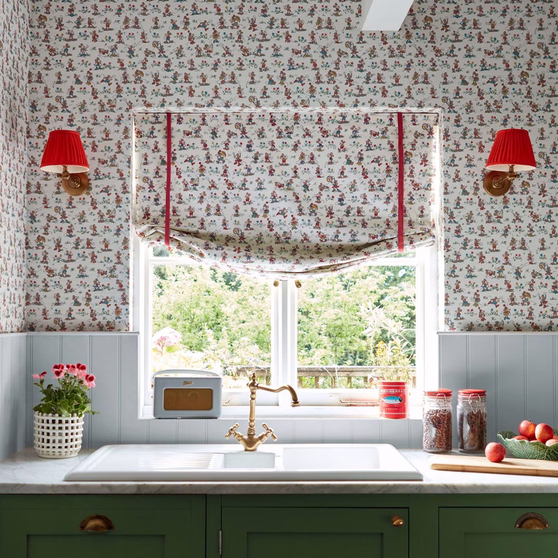 Kitchen with Mickey & Minnie fabric on a Roman blind above the window, with matching wallpaper and a window seat blind layered below.