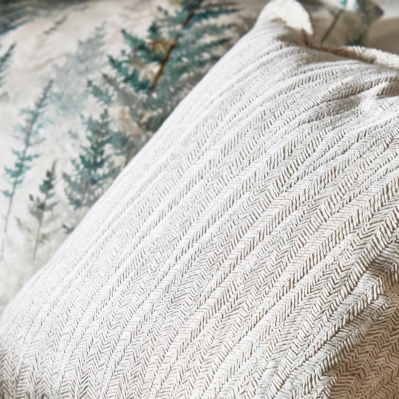 Cushions upholstered in a pale herringbone woven fabric, with a patterned fabric visible behind.