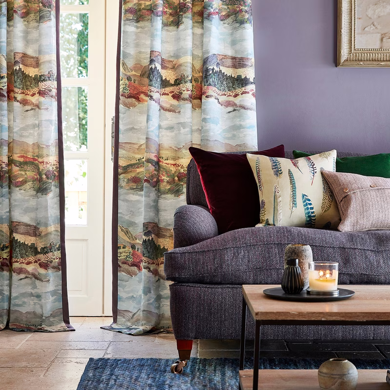 Living room with Elysian fabric used for curtains beside a window and sofa cushions on a sofa.
