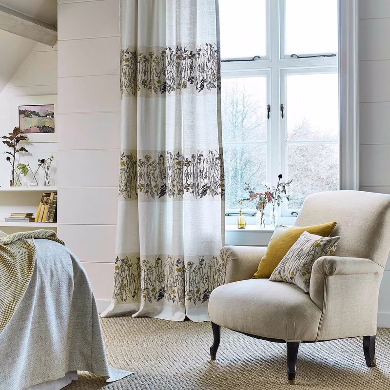 Light-filled room with sheer patterned curtains, a matching cushion on an upholstered armchair, and a bed throw; the fabric has been made up as several things