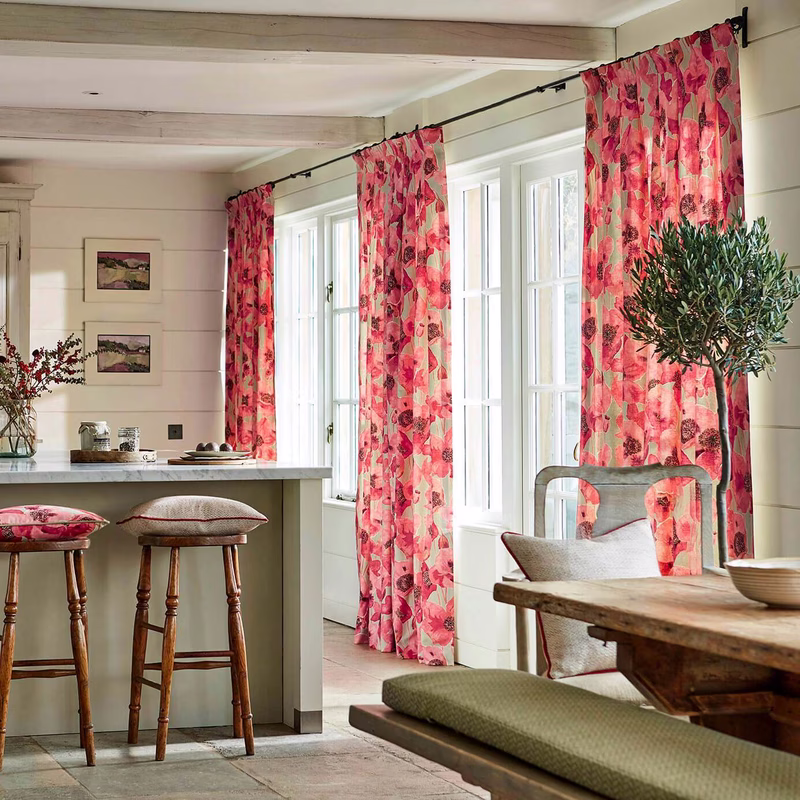 Bright kitchen-dining room with Embleton made up as curtains at tall windows, plus matching upholstered stools and cushions.