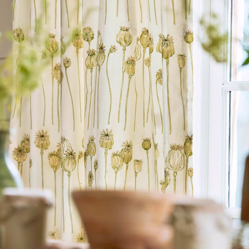 A room with a poppy pod patterned fabric shown as curtains by a window.