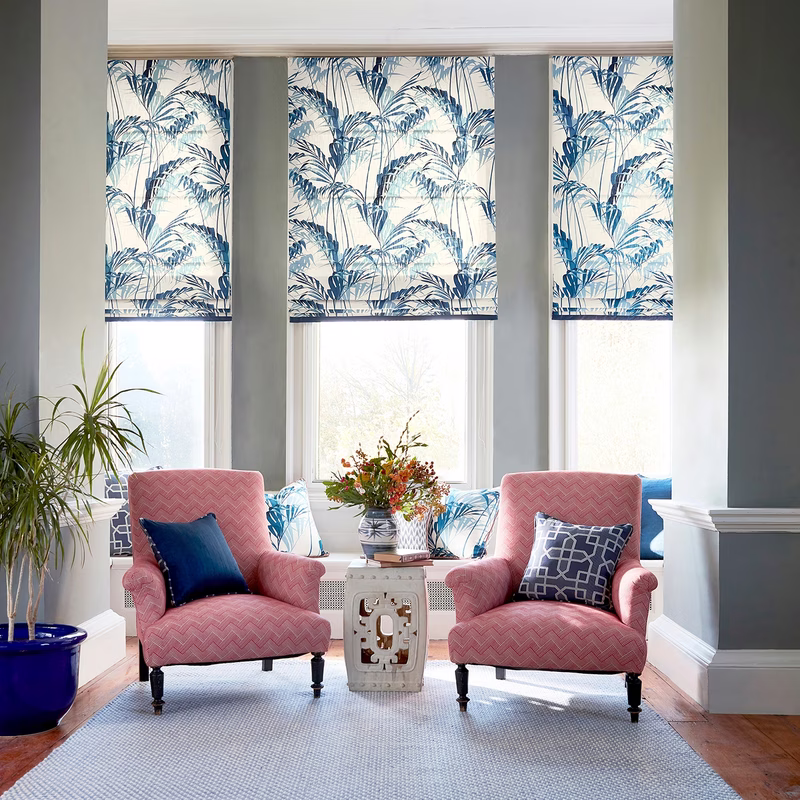 Sitting room with Palm House fabric made up as three Roman blinds over the windows.