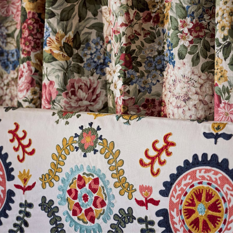 Sample fabric panels showing a floral print curtain above and an embroidered motif fabric below.