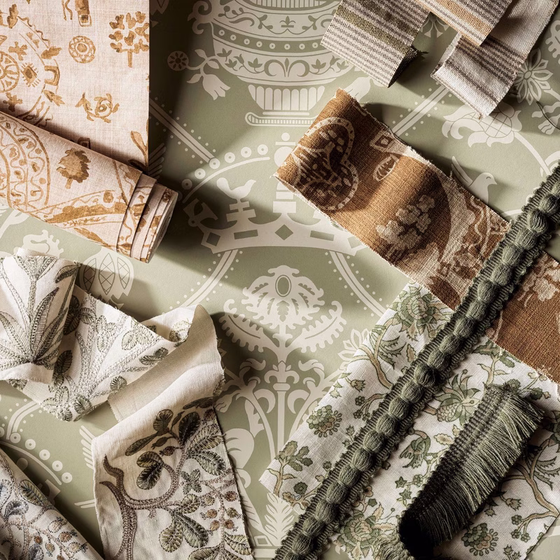 Fabric swatches and trims arranged on a printed olive-and-cream floral background, with the cloth shown as folded lengths and sample pieces.