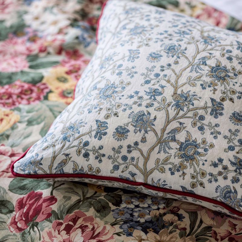 Close-up of patterned floral fabric made up as a piped cushion on top of matching upholstery fabrics.