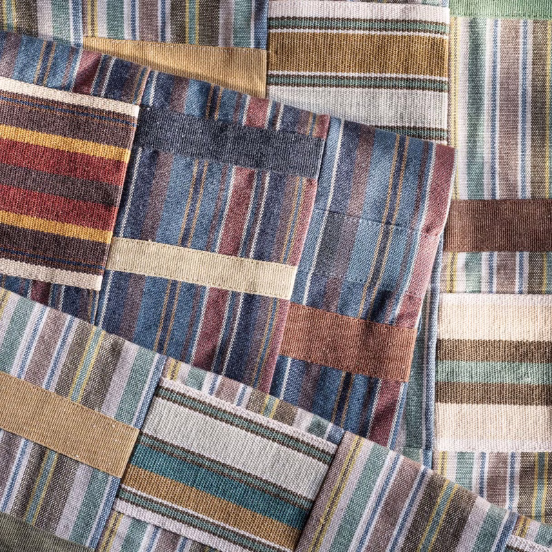 Close-up of layered striped fabric swatches from a collection, shown as flat lengths of cloth.