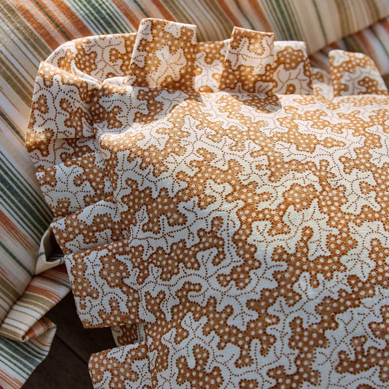 Patterned fabric made up as cushions on a striped upholstered seat.