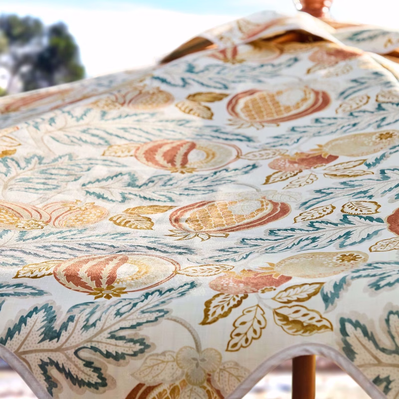 Close-up of patterned fabric draped over an outdoor chair, showing a printed upholstery cloth with melon and leaf motifs.