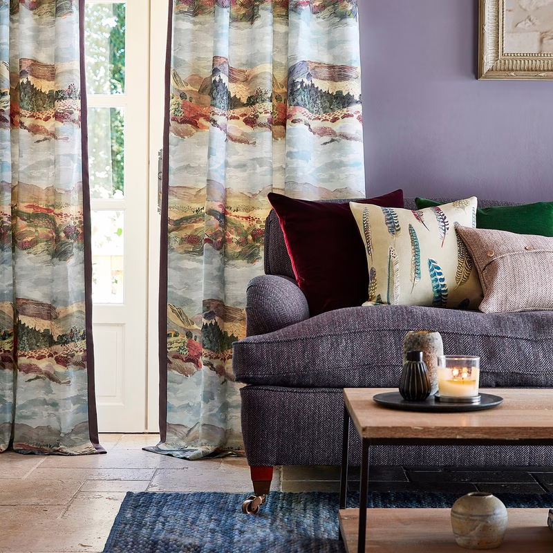 Living room with patterned curtains at a glass door, and the cloth also used as a sofa upholstery and cushion cover.