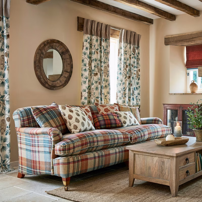 A living room with plaid upholstery on a sofa, matching curtains at the window, and patterned cushions.
