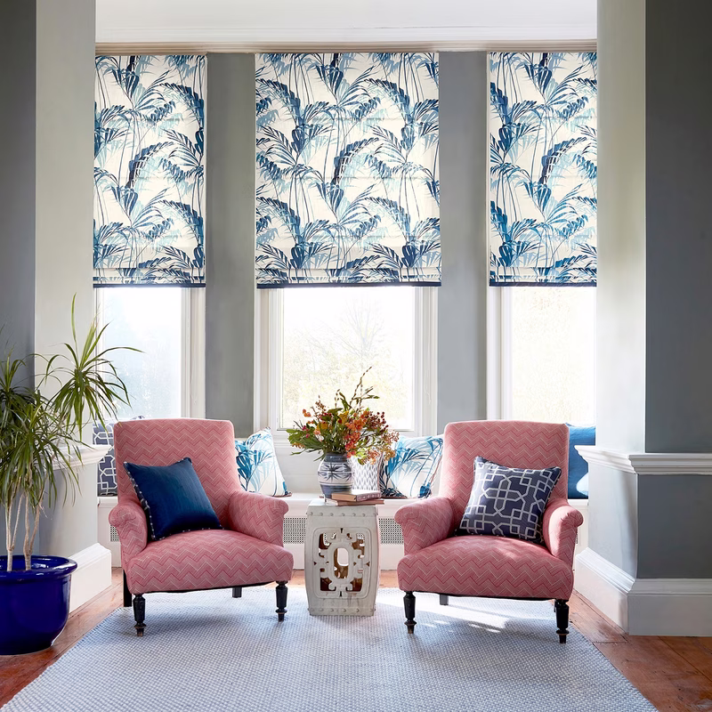 Bright sitting room with three windows dressed in blue-and-white patterned Roman blinds.