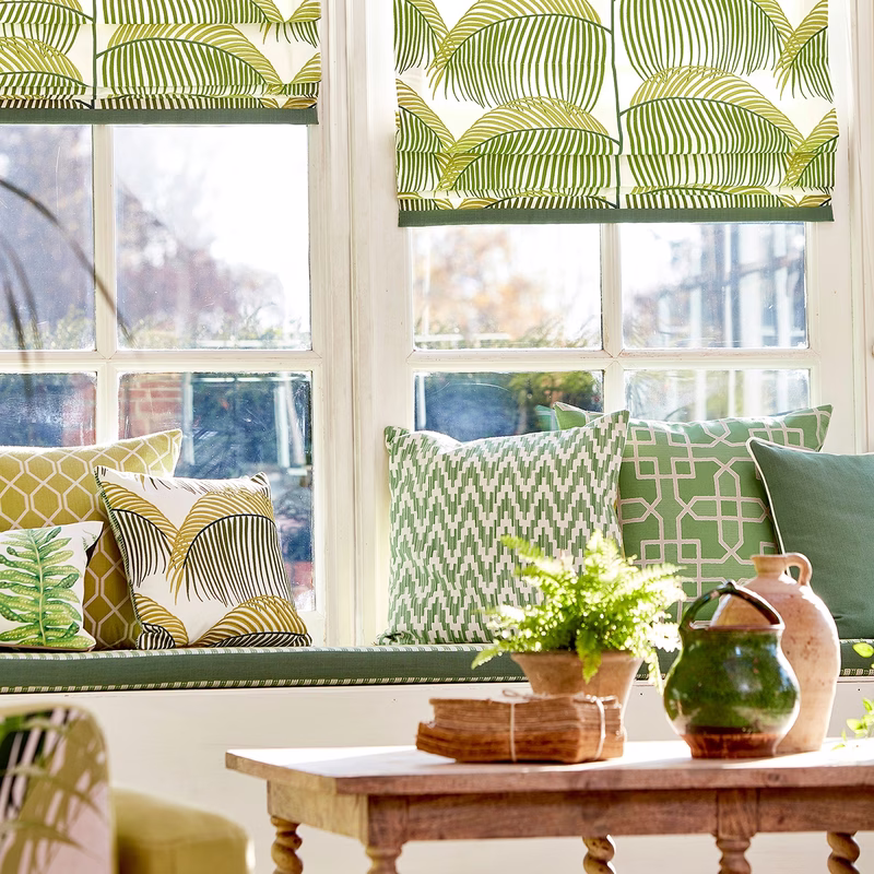 Sunlit room with window seat cushions and matching Roman blinds in a green leaf pattern.