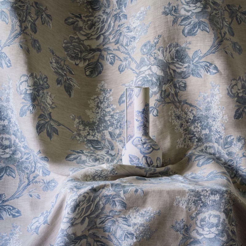 Fabric draped as a flat length of cloth in a studio setup, with a matching vase on a folded cloth ledge.