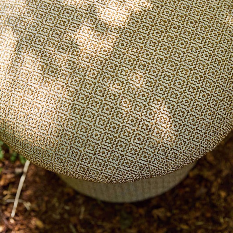 Close-up of a round upholstered footstool covered in patterned fabric.
