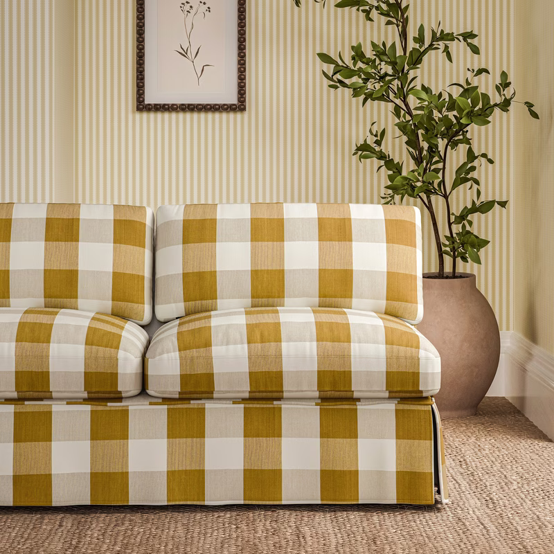 Living room with a sofa upholstered in yellow-and-white check fabric, with matching wall covering behind it.
