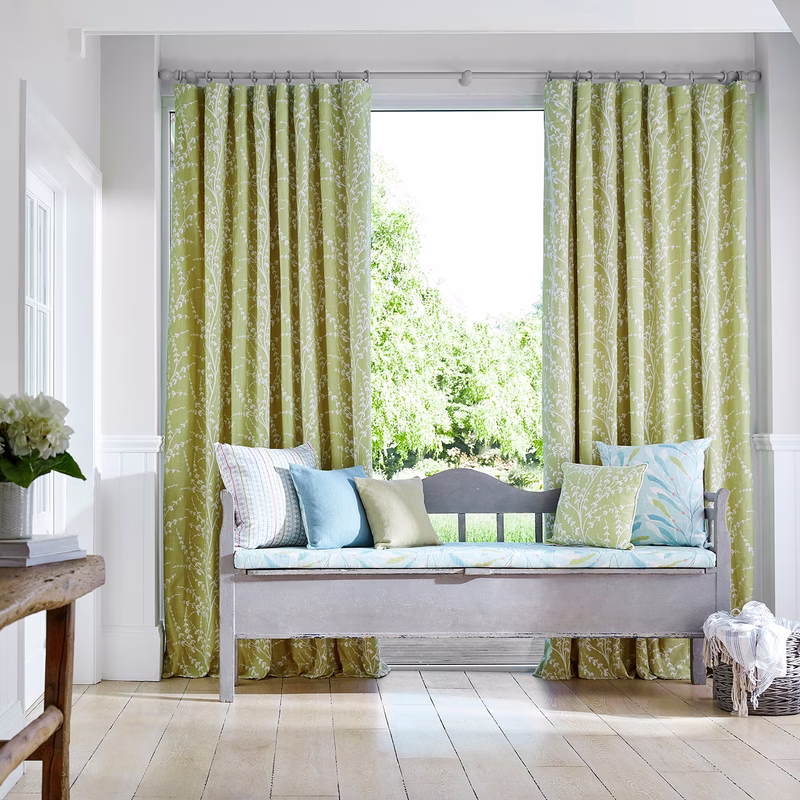 Bright room with a bench in front of a window, with Armeria Trail made up as full-length curtains and a bench cushion, plus cushions.