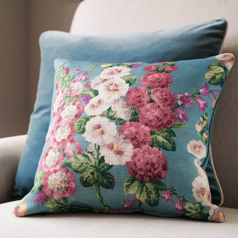 A sofa with a floral patterned cushion in front of a plain blue cushion, showing the fabric made up as cushions.