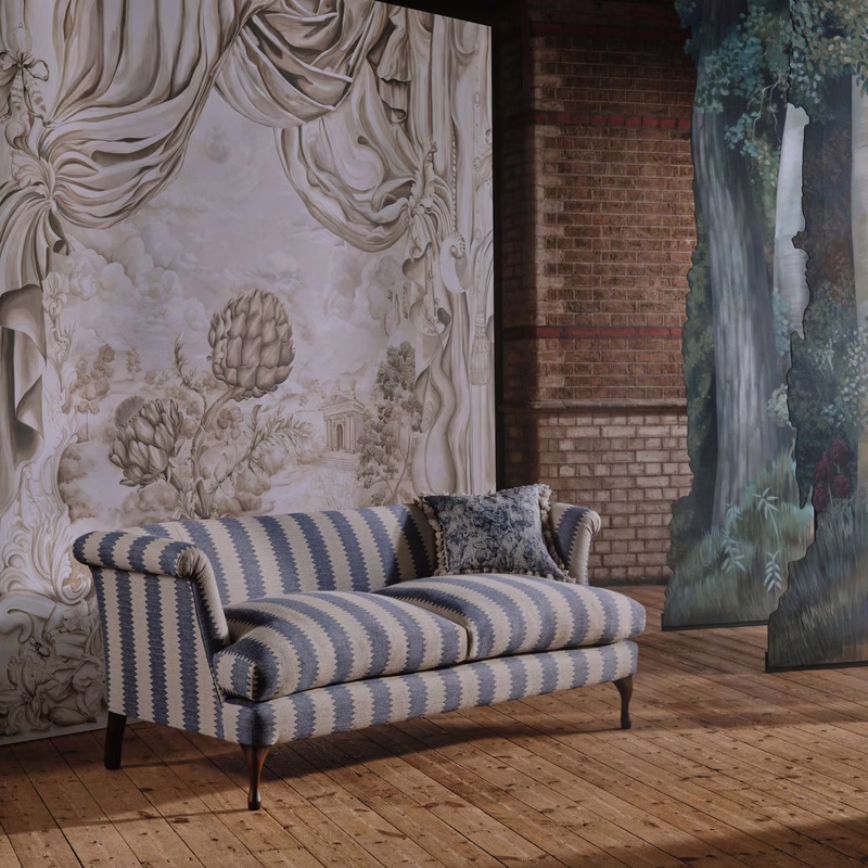 A striped upholstered sofa with a matching cushion sits in a room with decorative wall panels and brick walls.