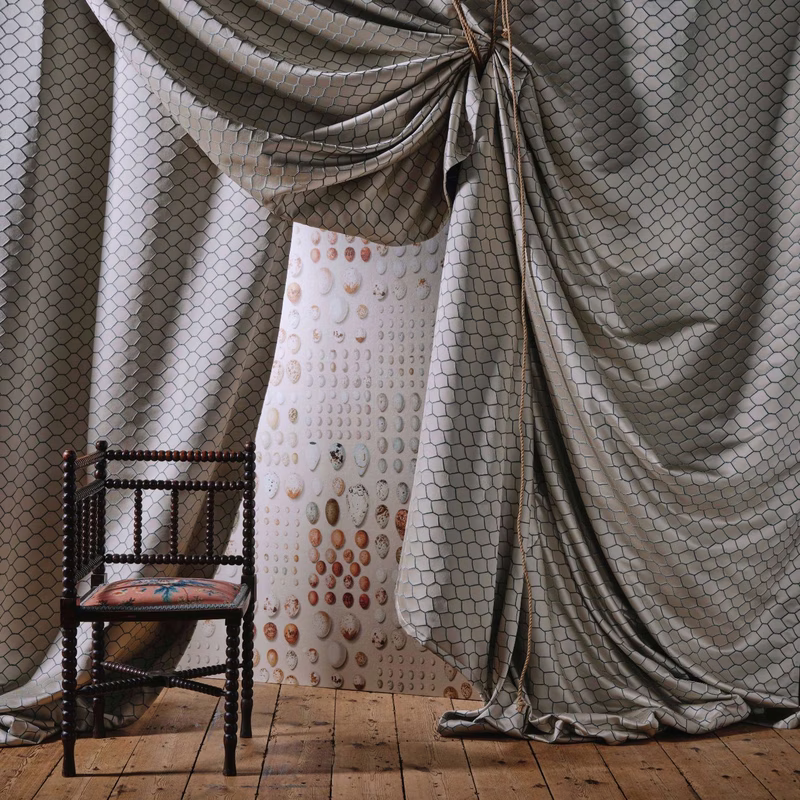 A room with Bantam Net fabric draped as curtains around a central panel, with a chair in front.