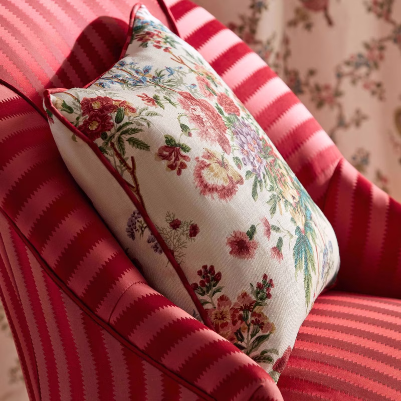 Two patterned cushions on a red striped upholstered chair, including a floral square cushion made up as a cushion.