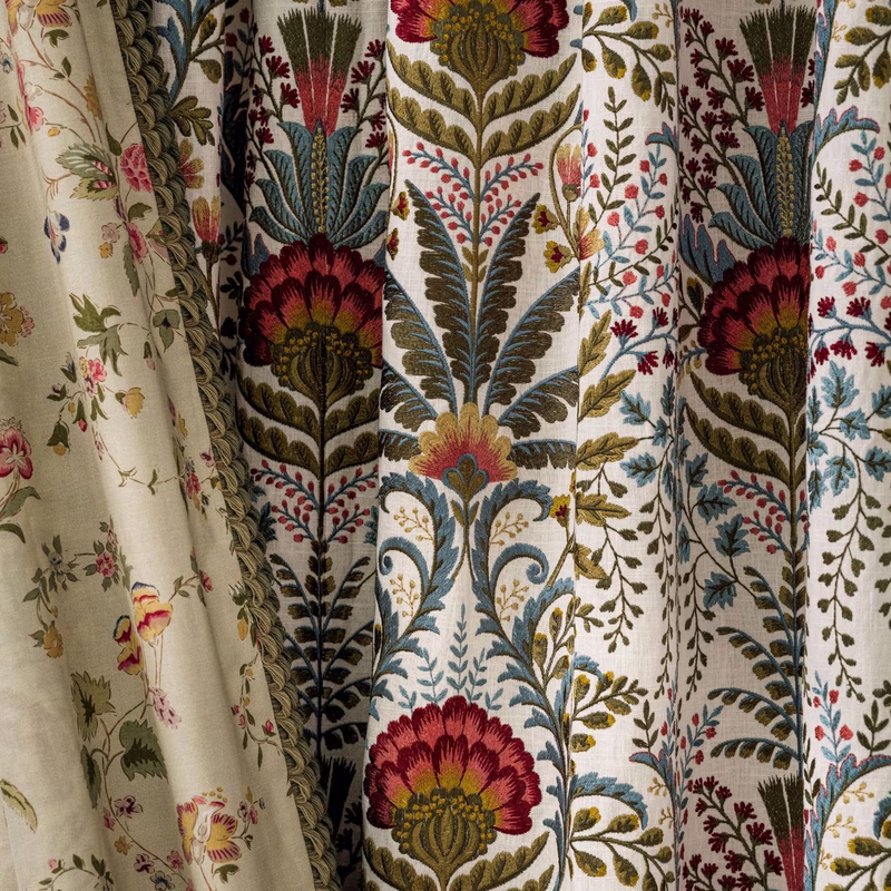 Sample room scene with patterned fabric made up as curtains, hanging in vertical folds with a floral and foliate motif.