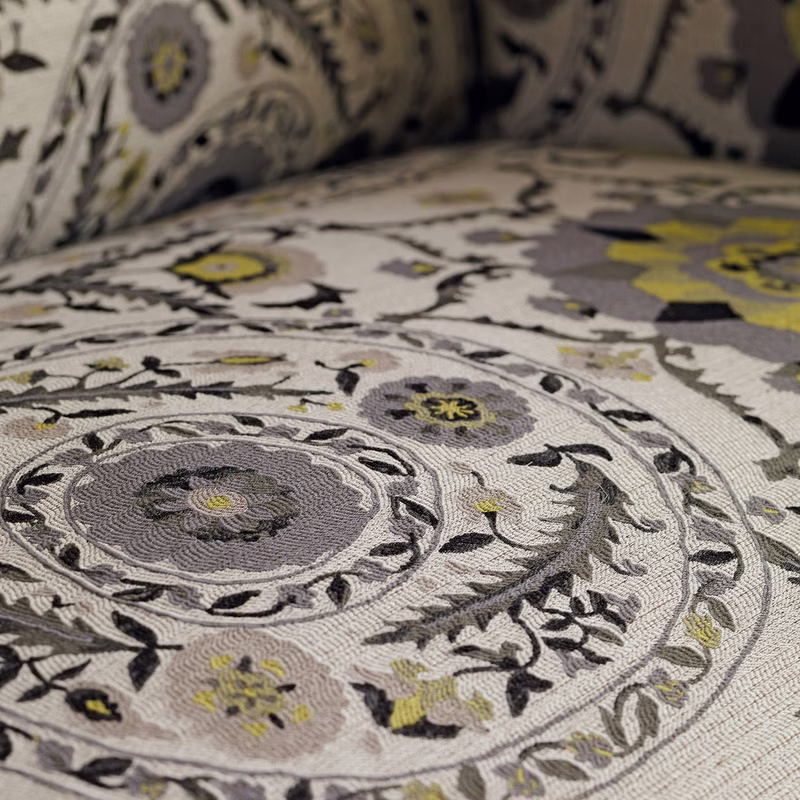 Close-up of patterned fabric upholstery with floral medallions on a curved seat back and cushion.