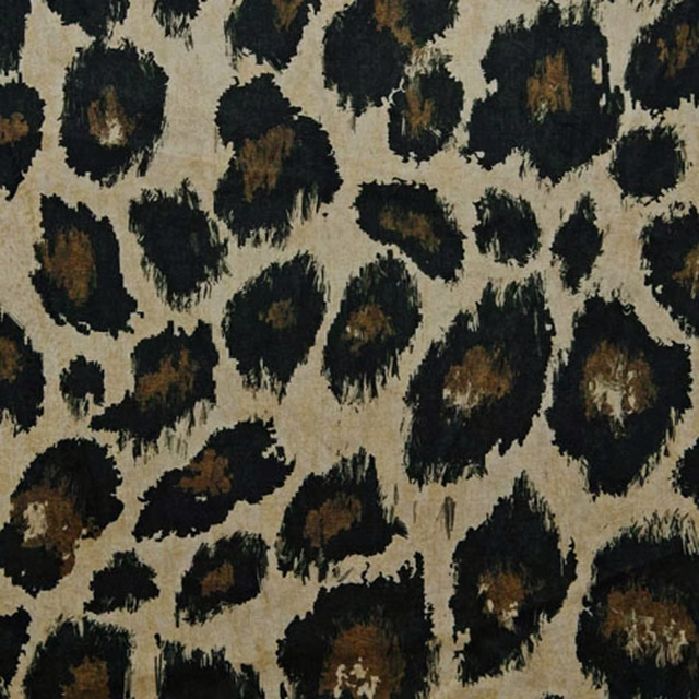 Warm beige fabric with irregular black and brown ocelot spots and textured brush-like edges