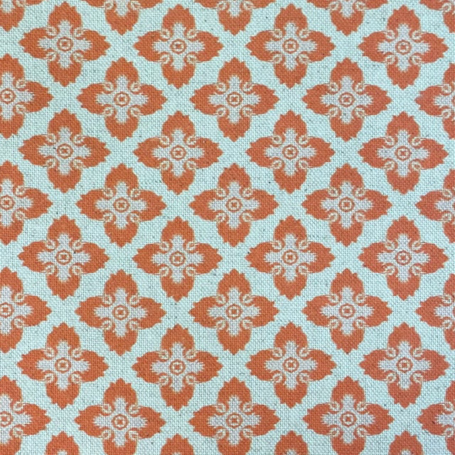 Turquoise woven fabric with repeating rust medallions and cream scroll details