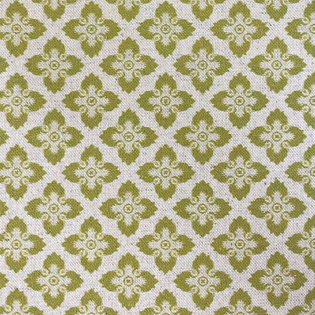 Muted olive-green quatrefoil flowers on a cream woven fabric ground