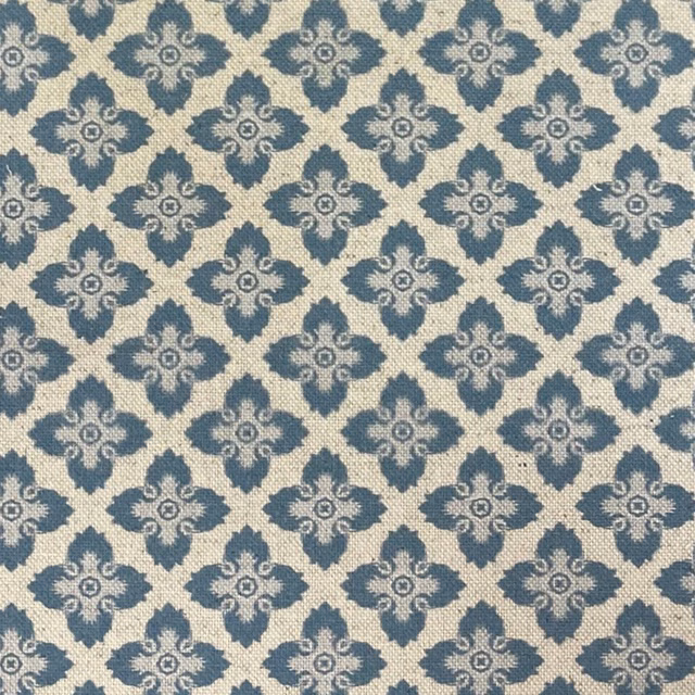 Blue-grey ornamental quatrefoils repeating across a softly textured cream woven fabric