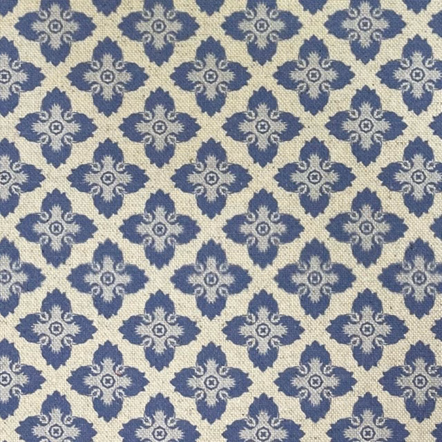 Warm cream woven ground with repeating slate-blue ornamental medallions and tactile texture